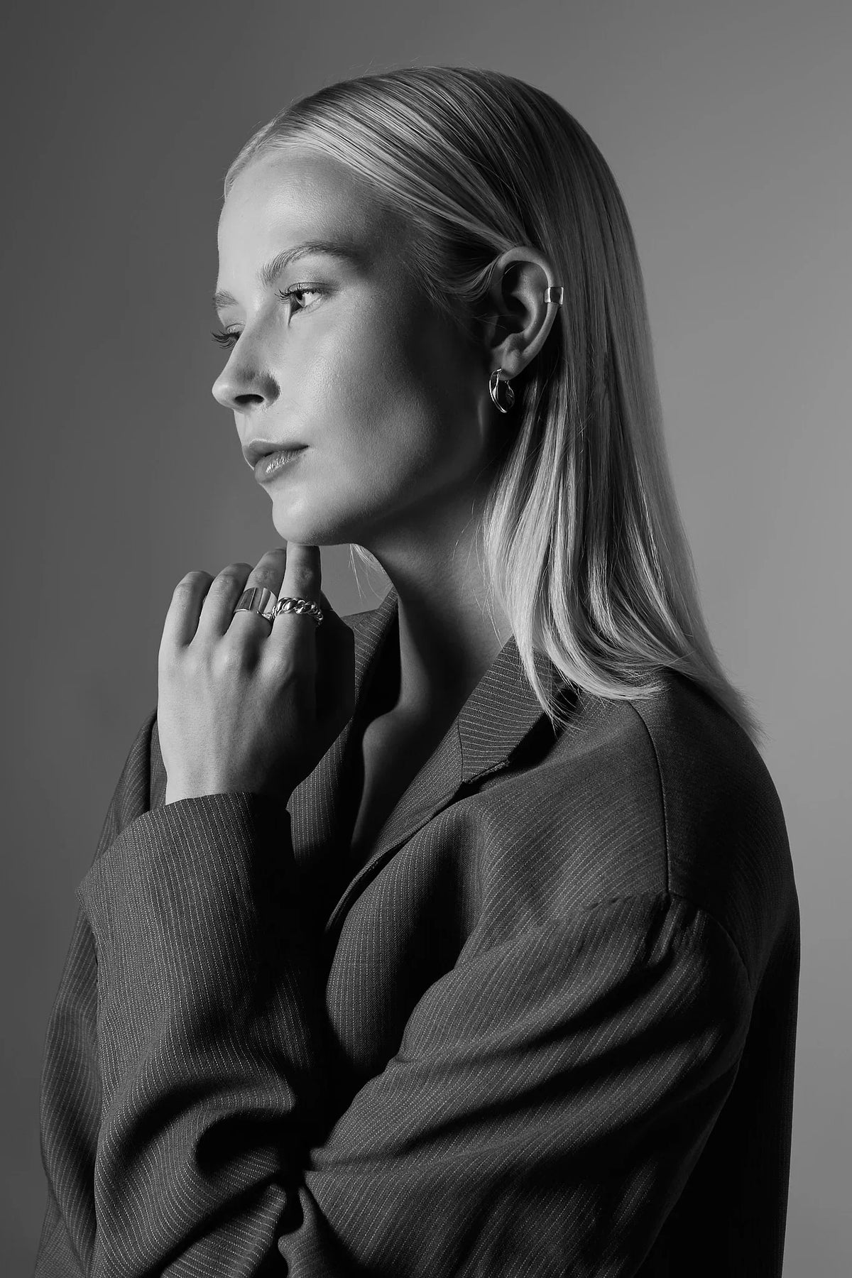 Woman wearing silver hoop earrings and rings, side profile, in black and white portrait