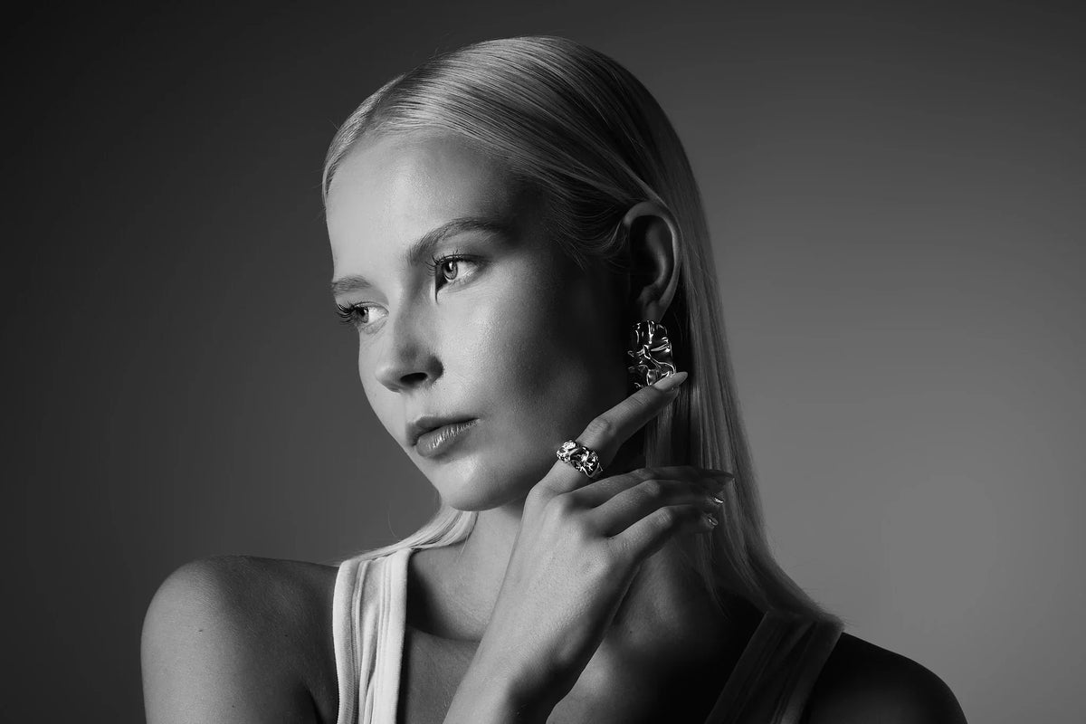 Woman wearing bold silver statement earrings and ring, minimalistic style jewelry