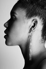 Profile of woman wearing silver chain tassel drop earring and hoop helix earring