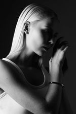 Woman in monochrome wearing minimalist silver bangle and ear cuff jewelry