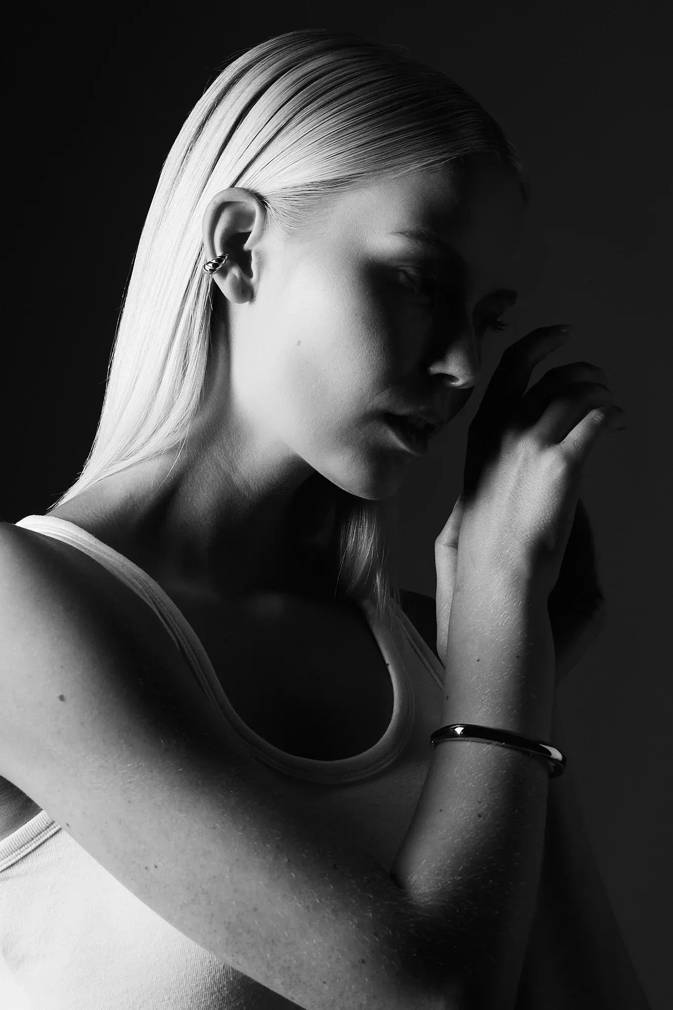 Woman in monochrome wearing minimalist silver bangle and ear cuff jewelry