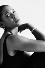 Woman in black dress wearing elegant bracelet and earrings, posing in studio