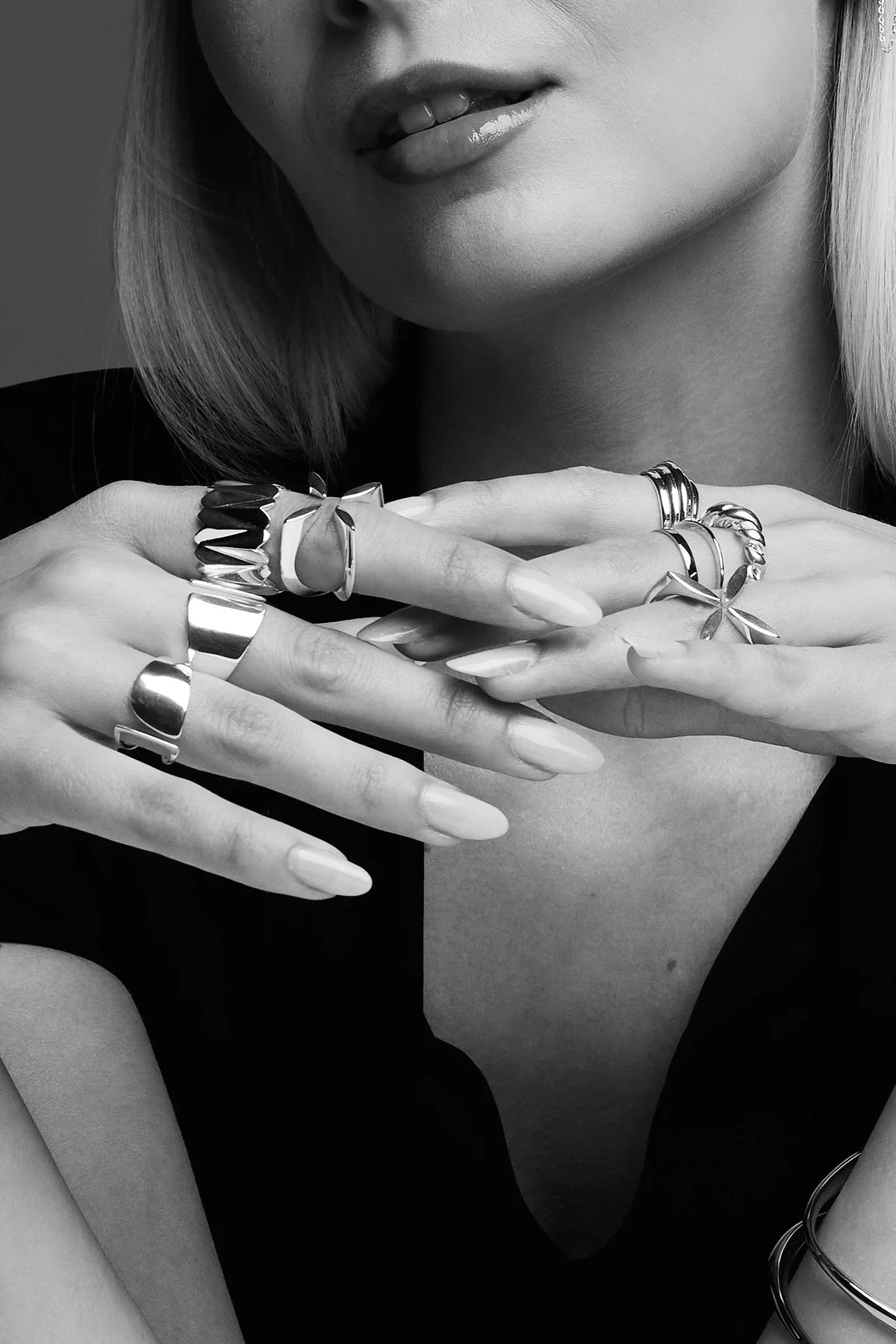 Woman wearing multiple bold silver rings and bracelets with manicured nails