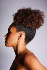 Woman wearing long gold chain drop earrings and gold hoop ear cuff, side profile view