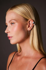 Woman wearing multiple silver ear cuffs and chain earrings, close-up profile view