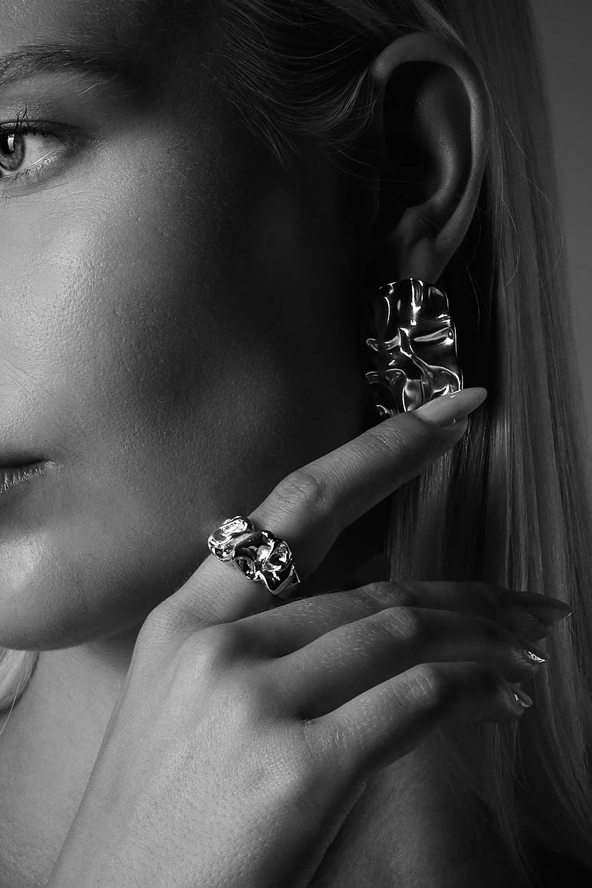Woman wearing sculpted silver statement ring and matching bold silver earring