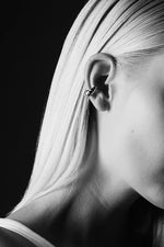 Close-up of a woman wearing a twisted silver ear cuff with straight blonde hair