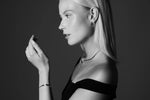 Woman wearing minimalist silver jewelry, including hoop earrings, necklace, and bracelet