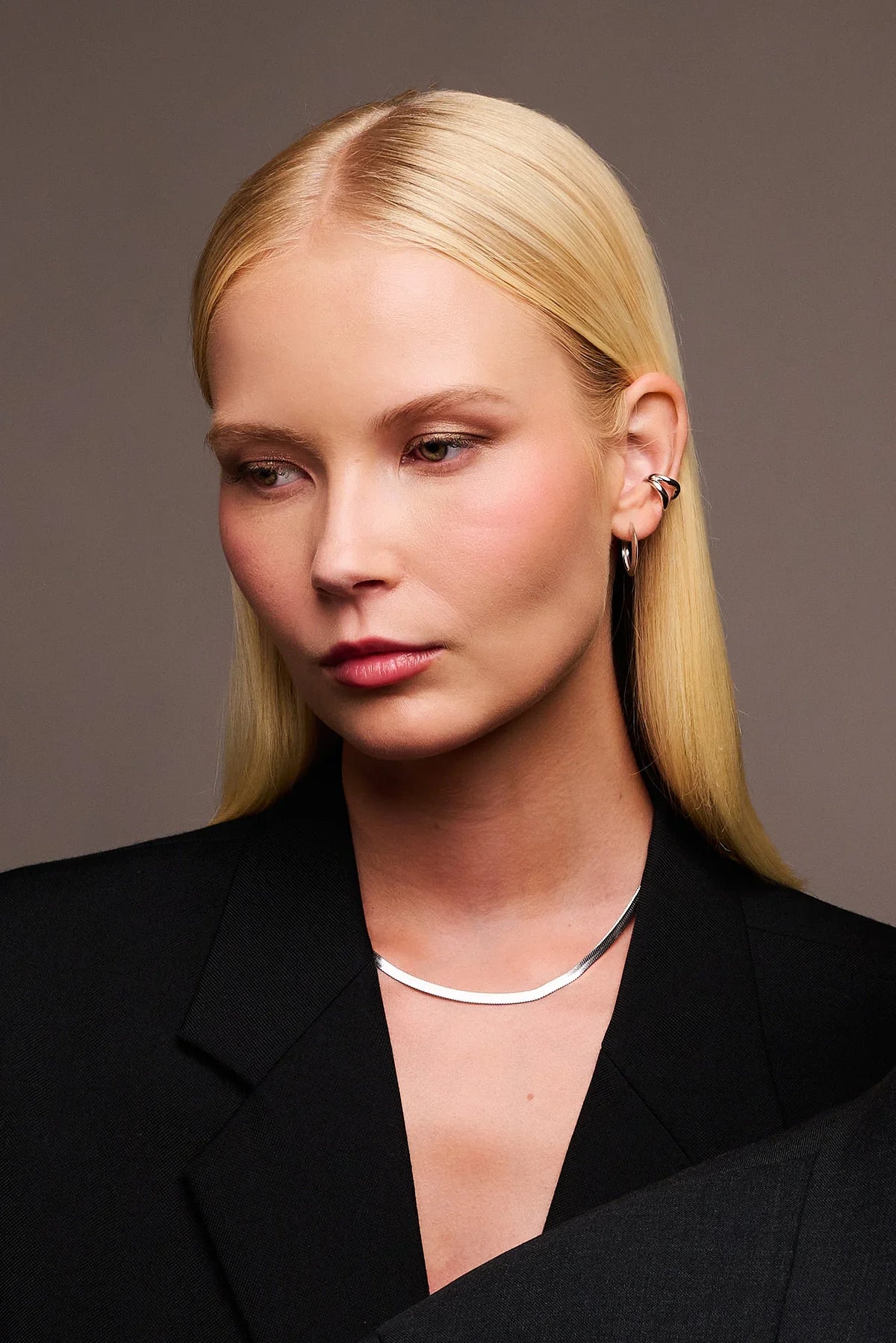 Woman wearing minimalist silver choker necklace and contemporary silver ear cuff with hoop earring
