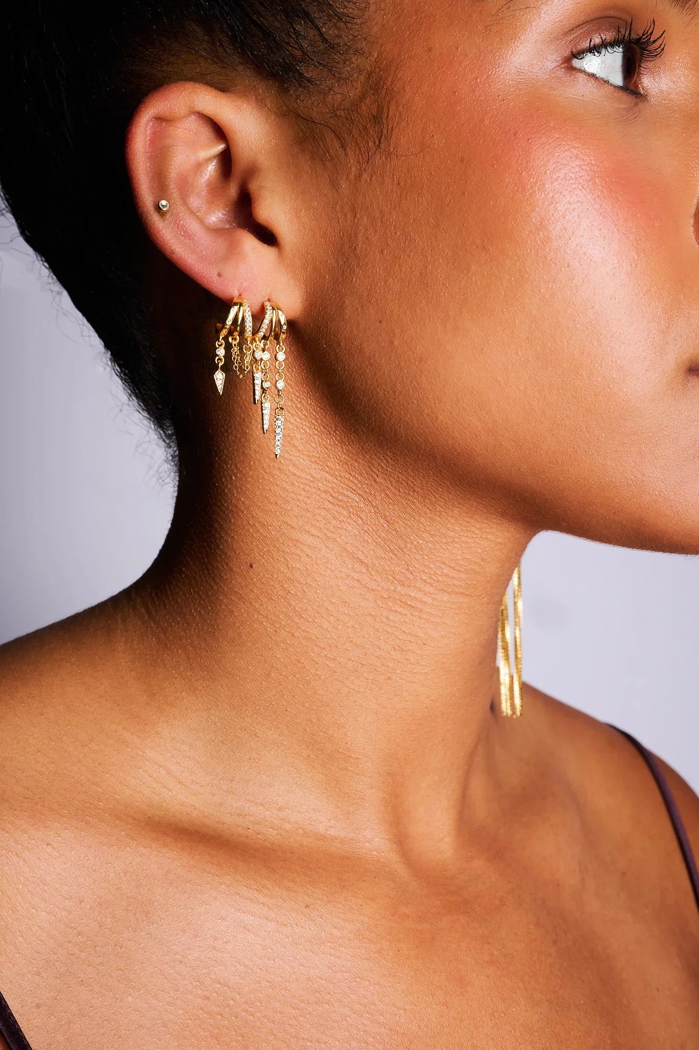 Woman wearing layered gold hoop earrings with dangling charms