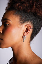 Close-up of woman wearing silver hoop and dangling earrings with ear cuff