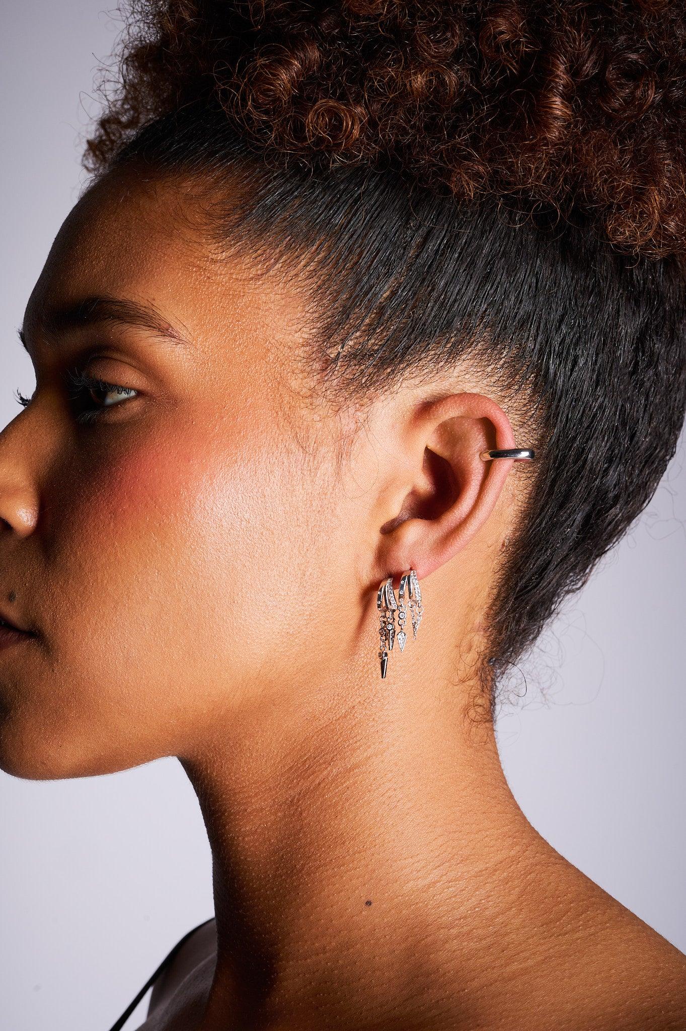 Close-up of woman wearing silver hoop and dangling earrings with ear cuff