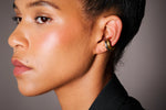 Woman wearing a double hoop ear cuff in gold and silver, close-up on ear
