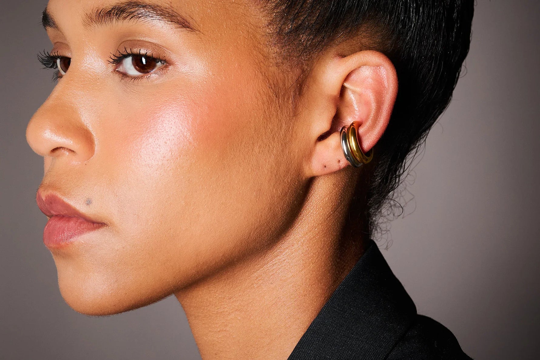 Woman wearing a double hoop ear cuff in gold and silver, close-up on ear