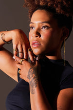 Woman wearing gold rings, bracelets, and earrings, showcasing modern jewellery style
