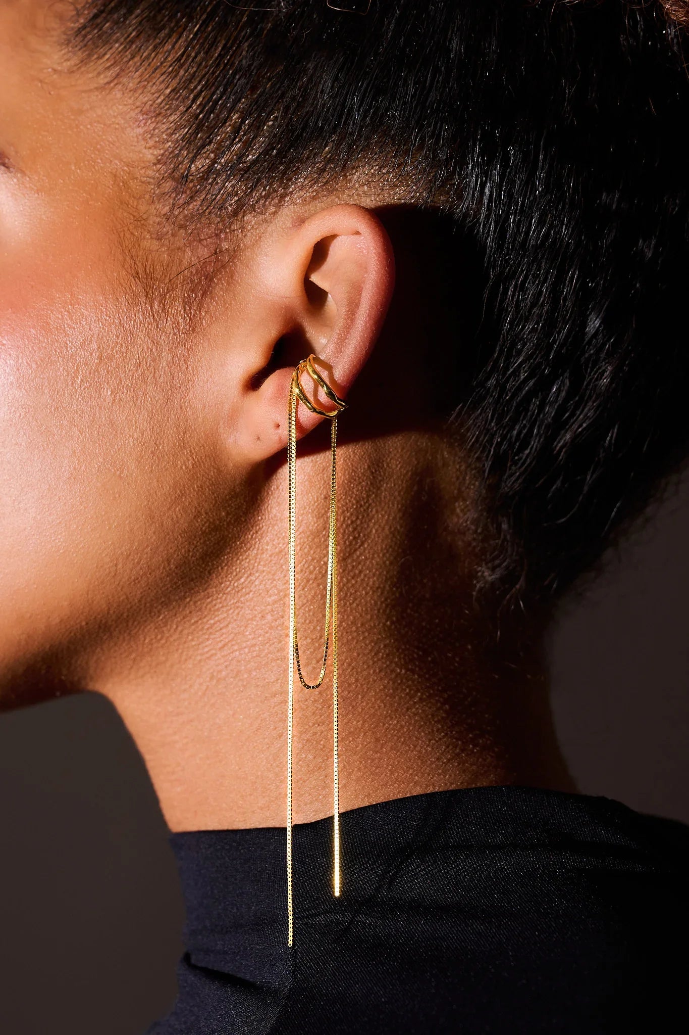 Close-up of ear wearing modern gold chain drop earring and ear cuff