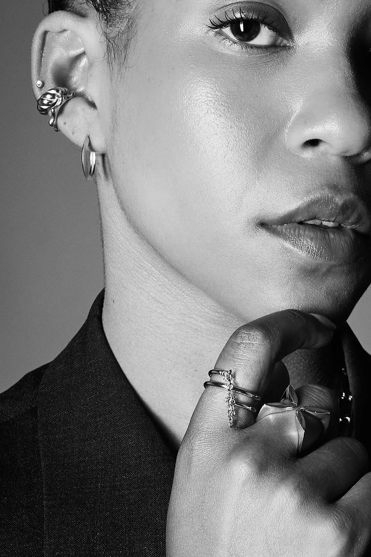 Close-up of woman wearing multiple silver rings and earrings, showcasing modern jewelry
