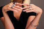Woman wearing multiple modern silver rings and bangles, showcasing elegant jewellery.