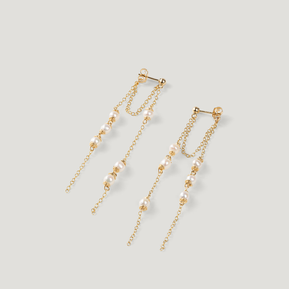 Pair of gold earrings with double chain strands and clustered pearls, on light background.