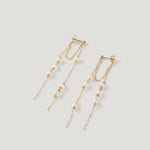 Pair of gold earrings with double chain strands and clustered pearls, on light background.