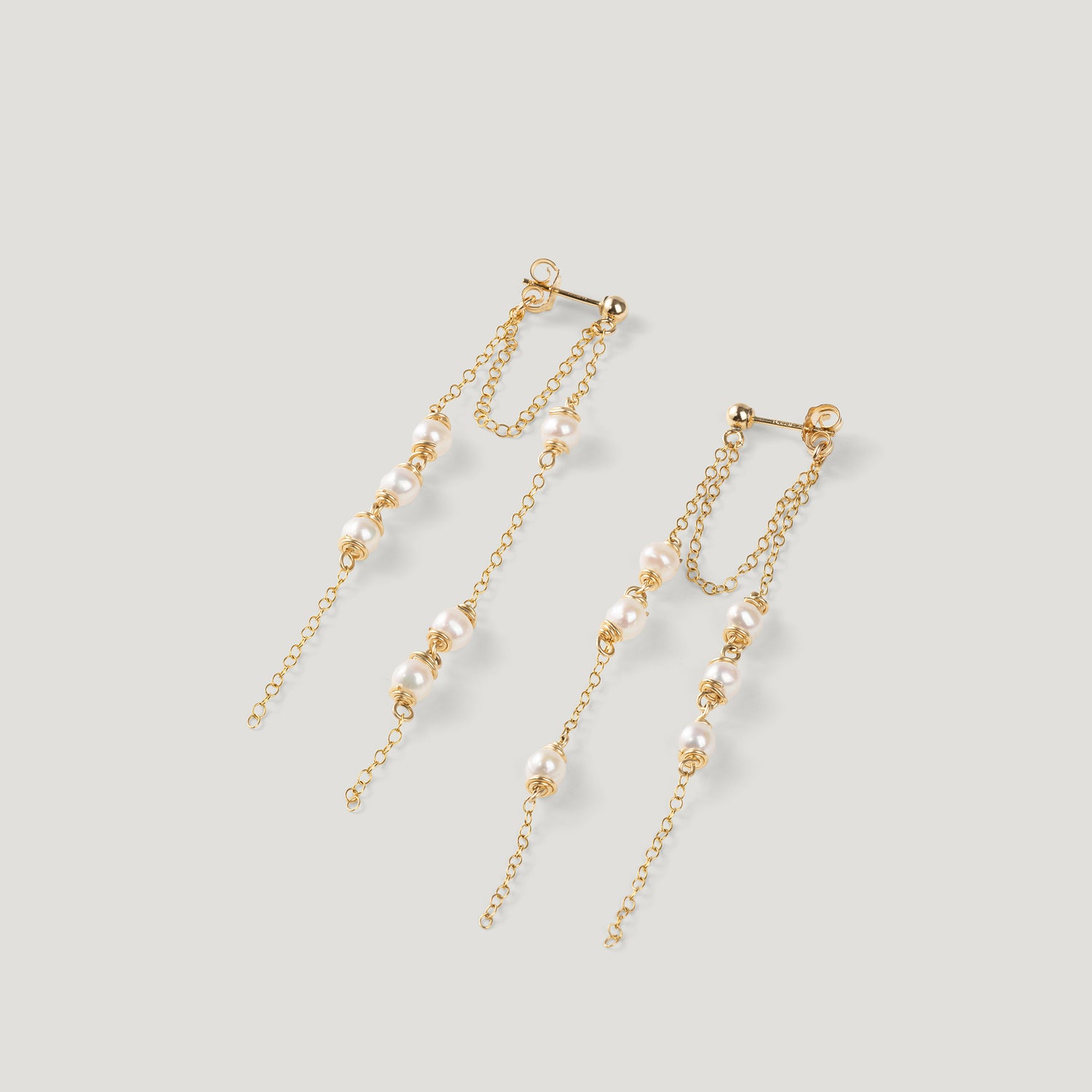 Pair of gold earrings with double chain strands and clustered pearls, on light background.