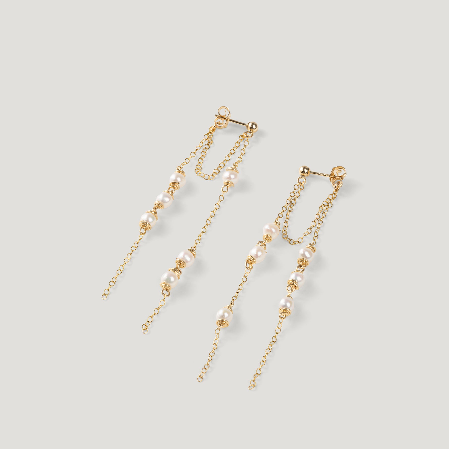 Pair of gold earrings with double chain strands and clustered pearls, on light background.