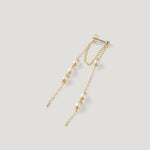 Single gold earring laid diagonally, showing two draping chains with pearls.