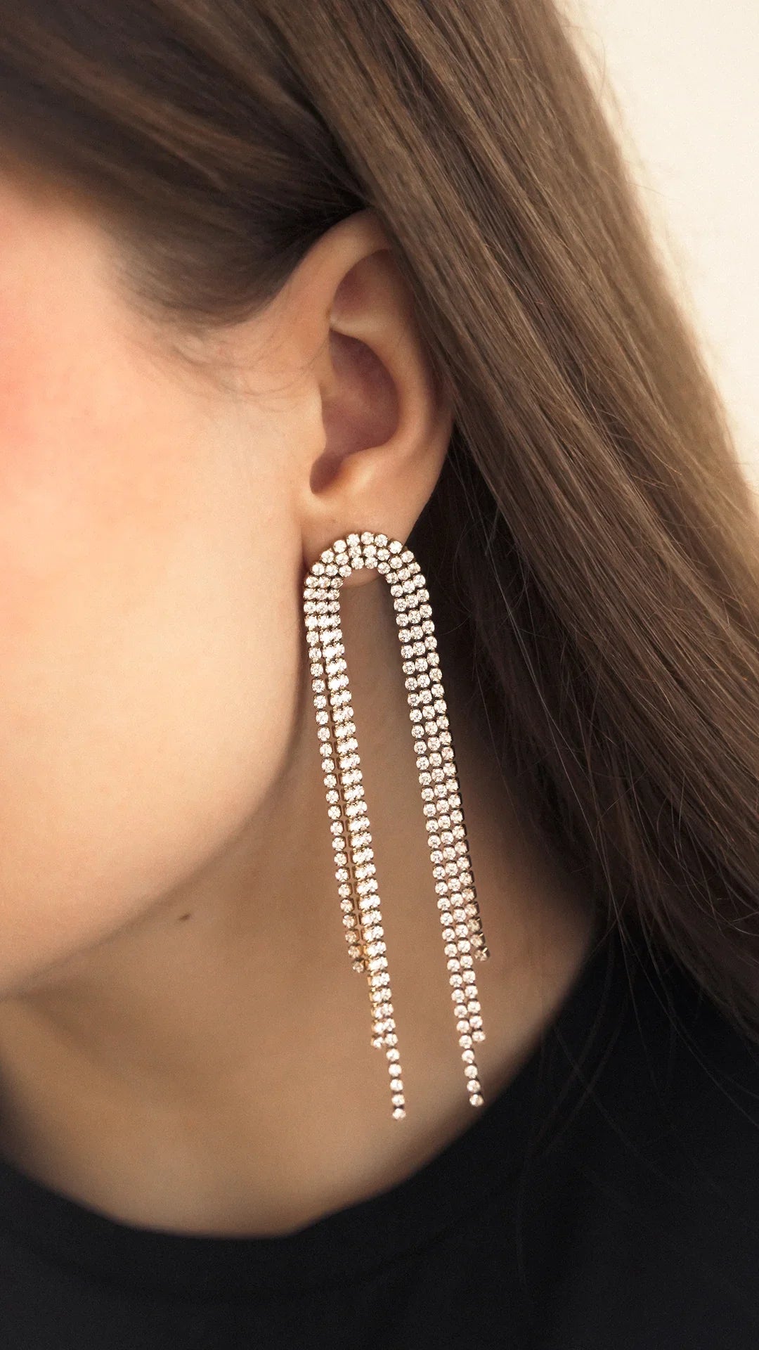 Woman wearing long crystal chain statement earrings with U-shaped design