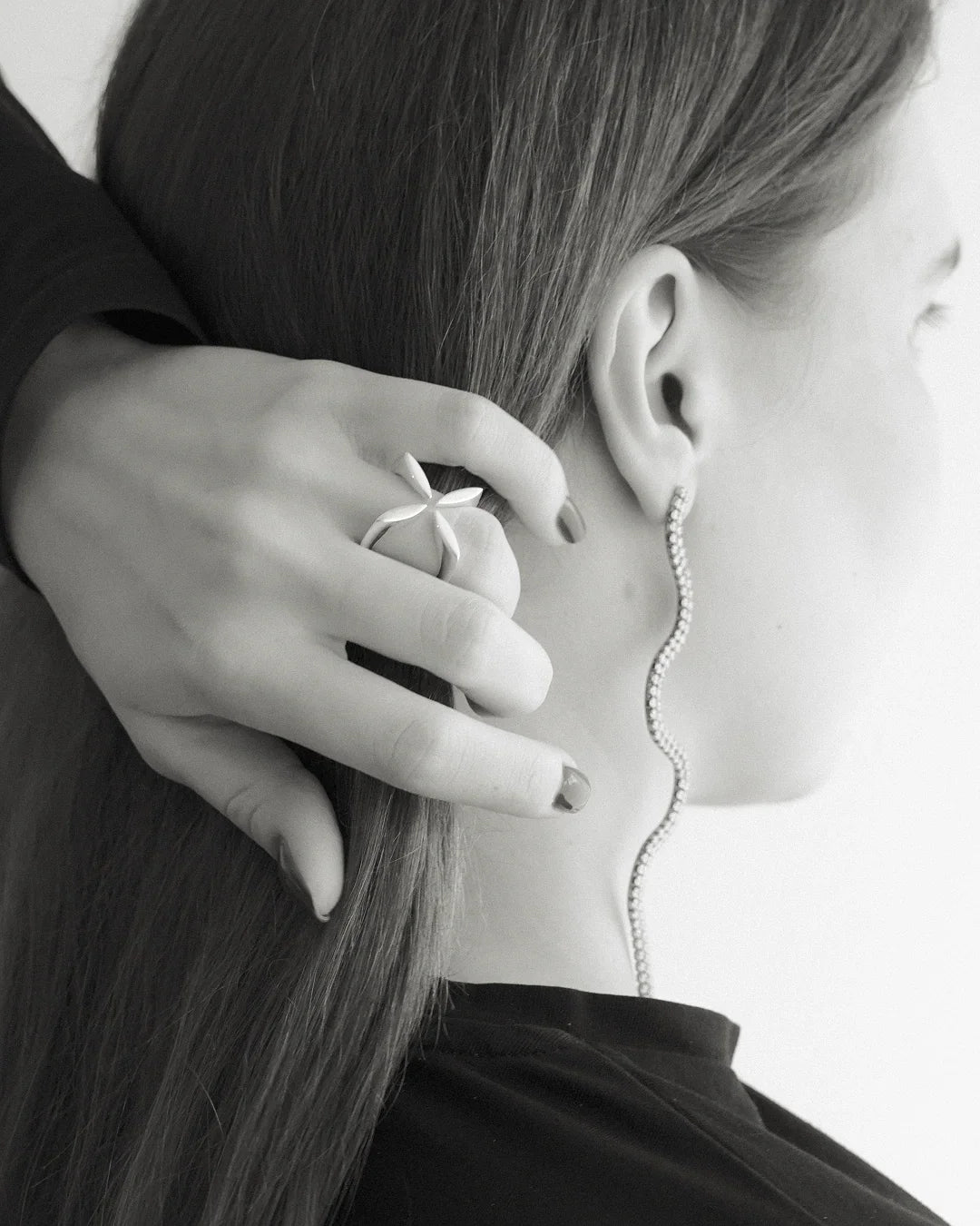 Woman wearing sculptural silver ring and wavy diamond drop earring