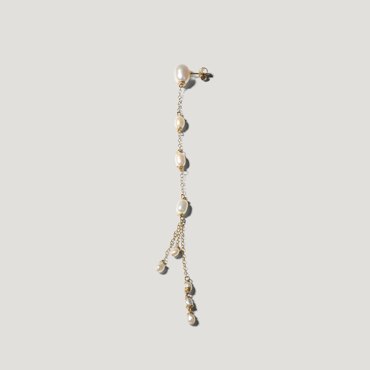 Single gold pearl drop earring hanging straight down, freshwater pearls along chain.