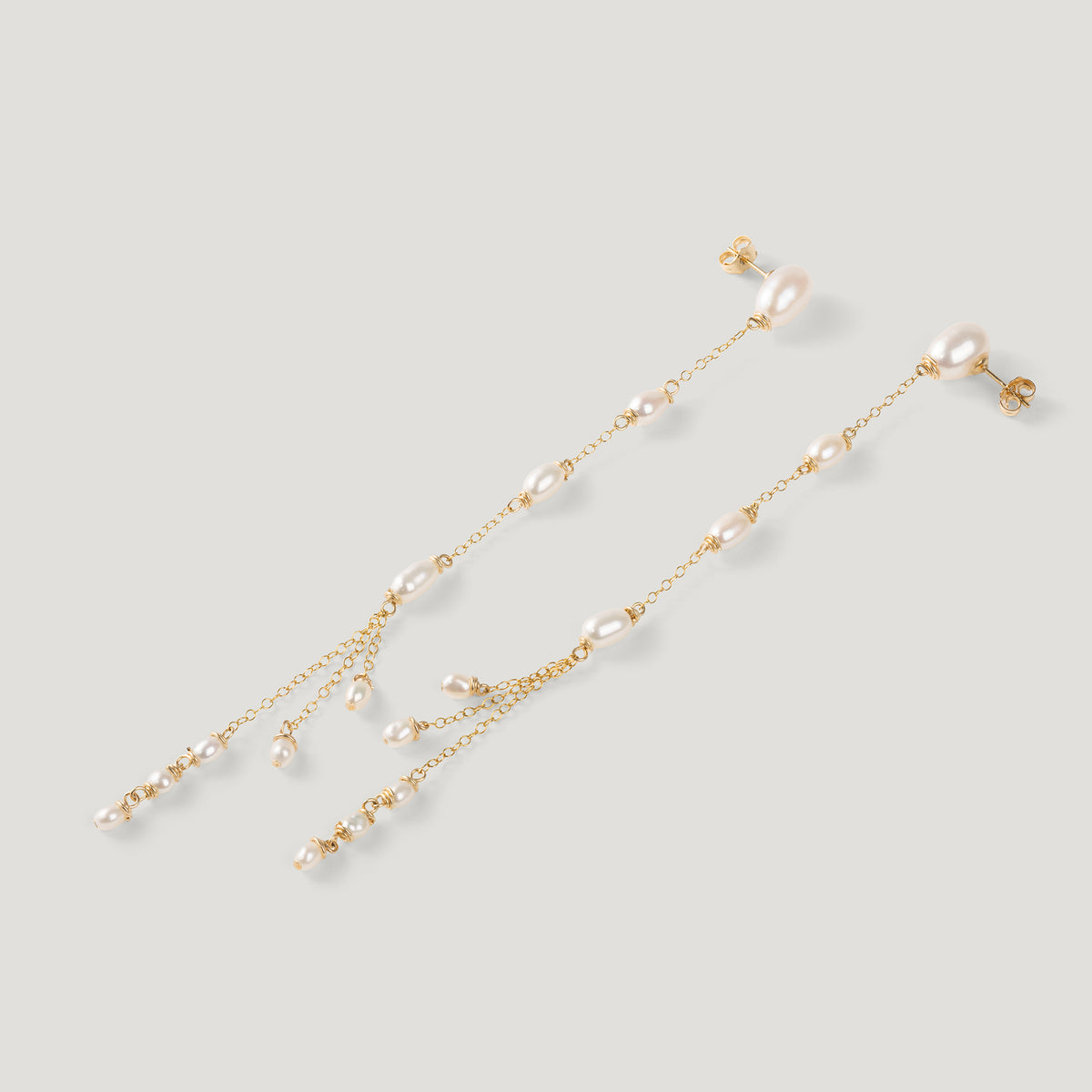 Pair of gold drop earrings with freshwater pearls along chain, clustered tassel ends.