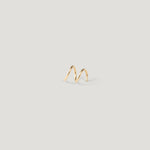 Single gold spiral twist huggie earring viewed from the side, on light background.