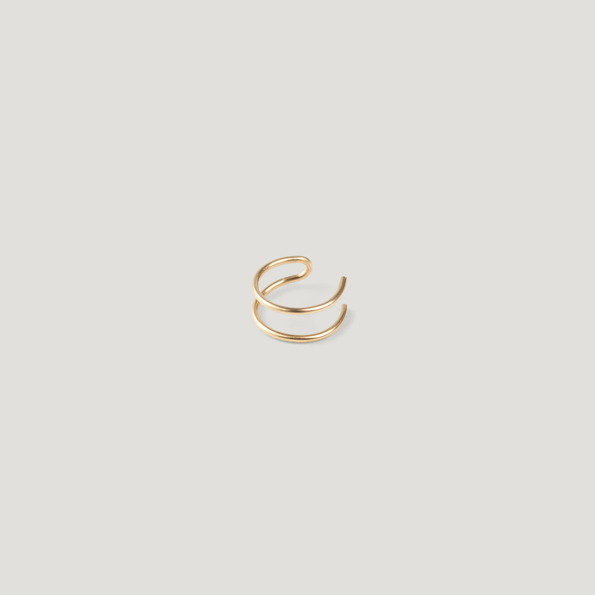 Single gold double-band ear cuff, close-up on light background.
