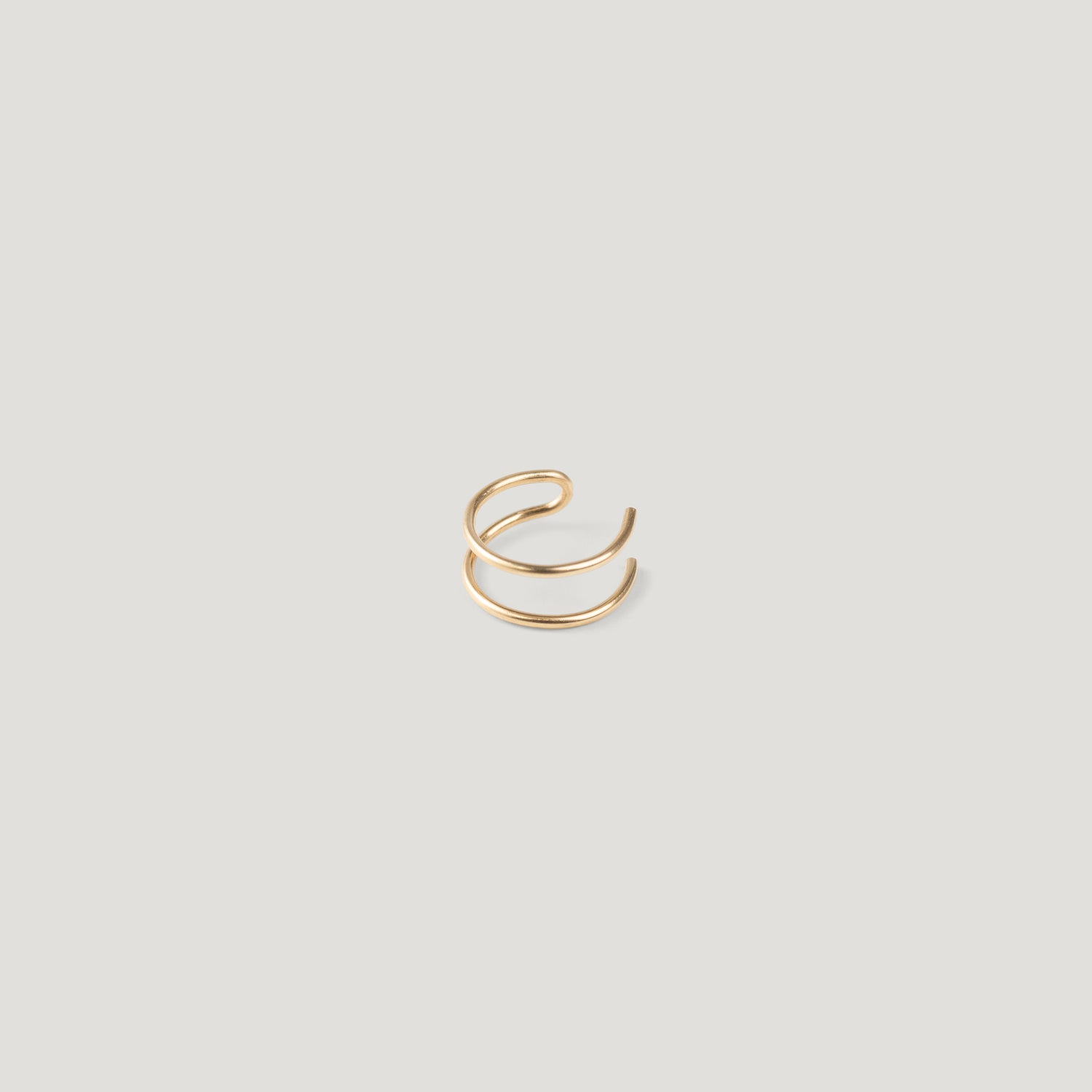 Single gold double-band ear cuff, close-up on light background.