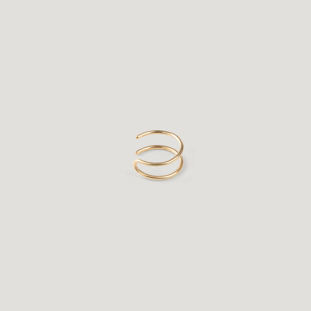 Single gold double-band ear cuff, viewed from a different angle on light background.