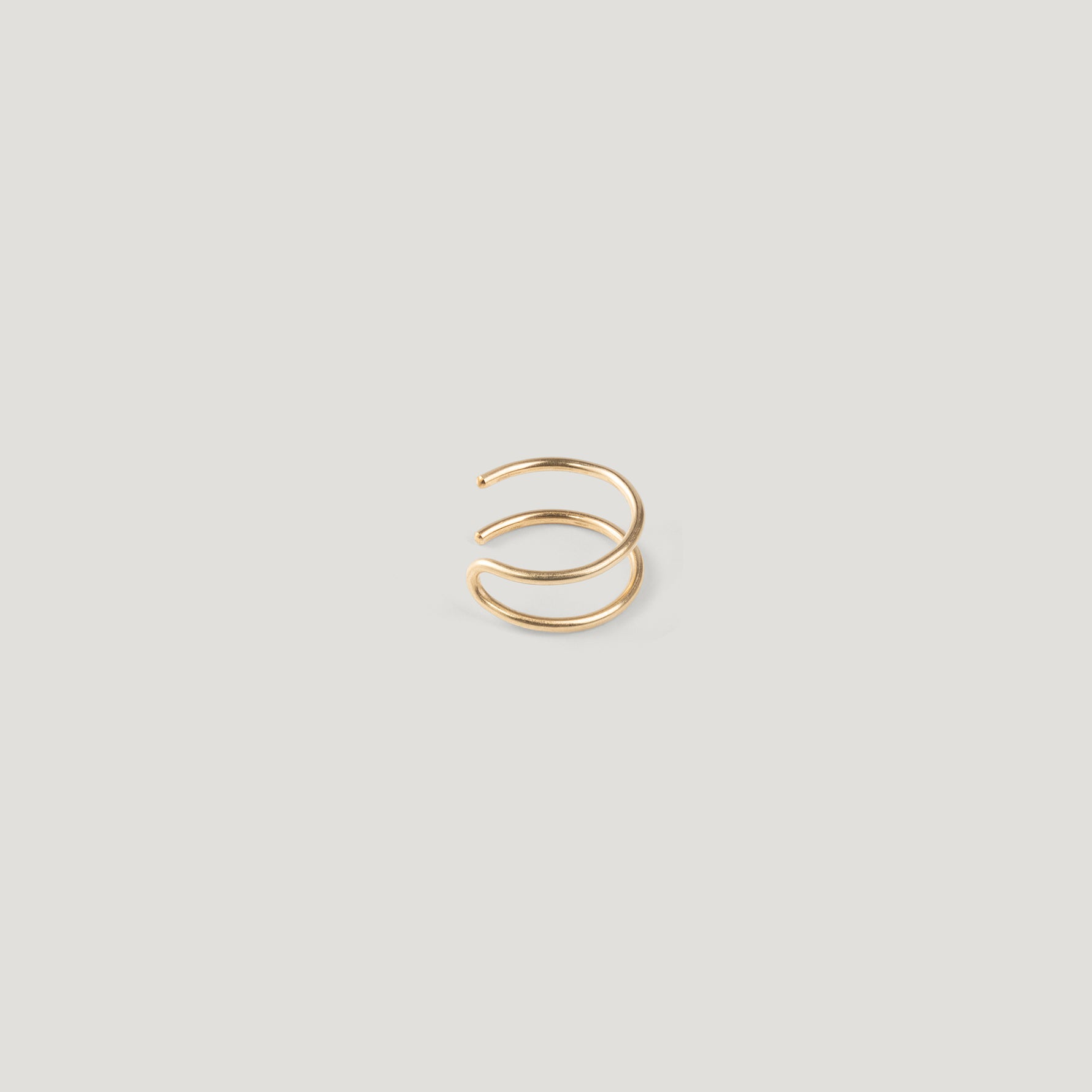 Single gold double-band ear cuff, viewed from a different angle on light background.