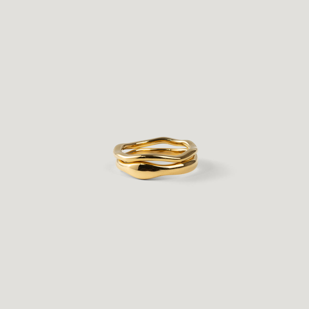 Two organic wavy gold rings stacked together, viewed side-on, one slim and one wide.