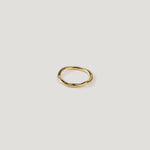 Small gold ring with an irregular wavy band, top-down view on light background.