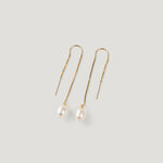 Pair of gold thread earrings, each with a dangling pearl, on light background.