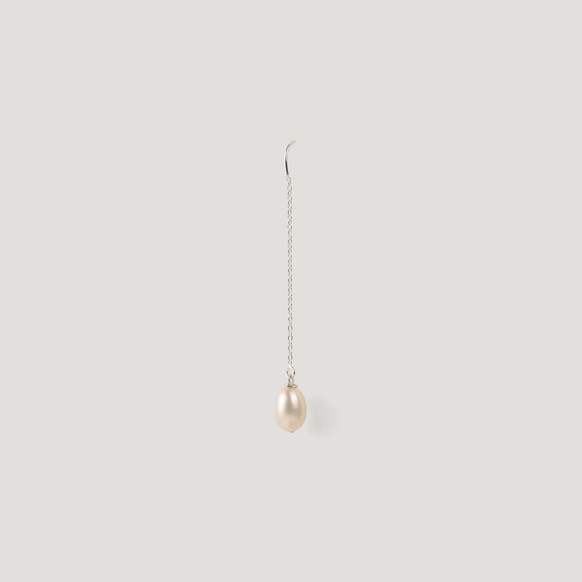 Single silver thread earring with a pearl drop, hanging vertically on light background.
