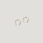 Pair of small gold thread earrings, one turned at an angle, close together.
