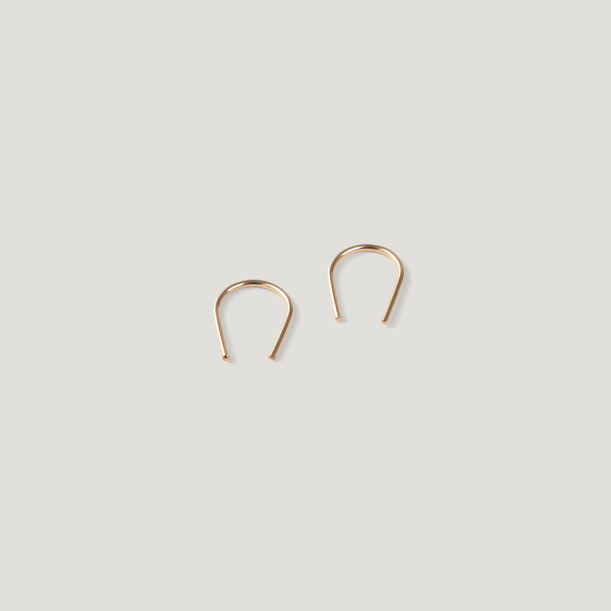 Pair of small gold thread earrings, one turned at an angle, close together.