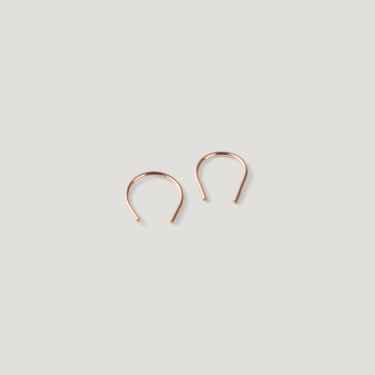 Pair of small rose gold thread earrings, one turned at an angle, close together.