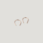 Pair of small rose gold thread earrings, one turned at an angle, close together.