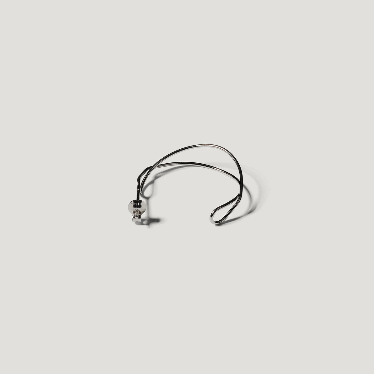 Single silver wire hoop earring laid flat, viewed from above on light background.