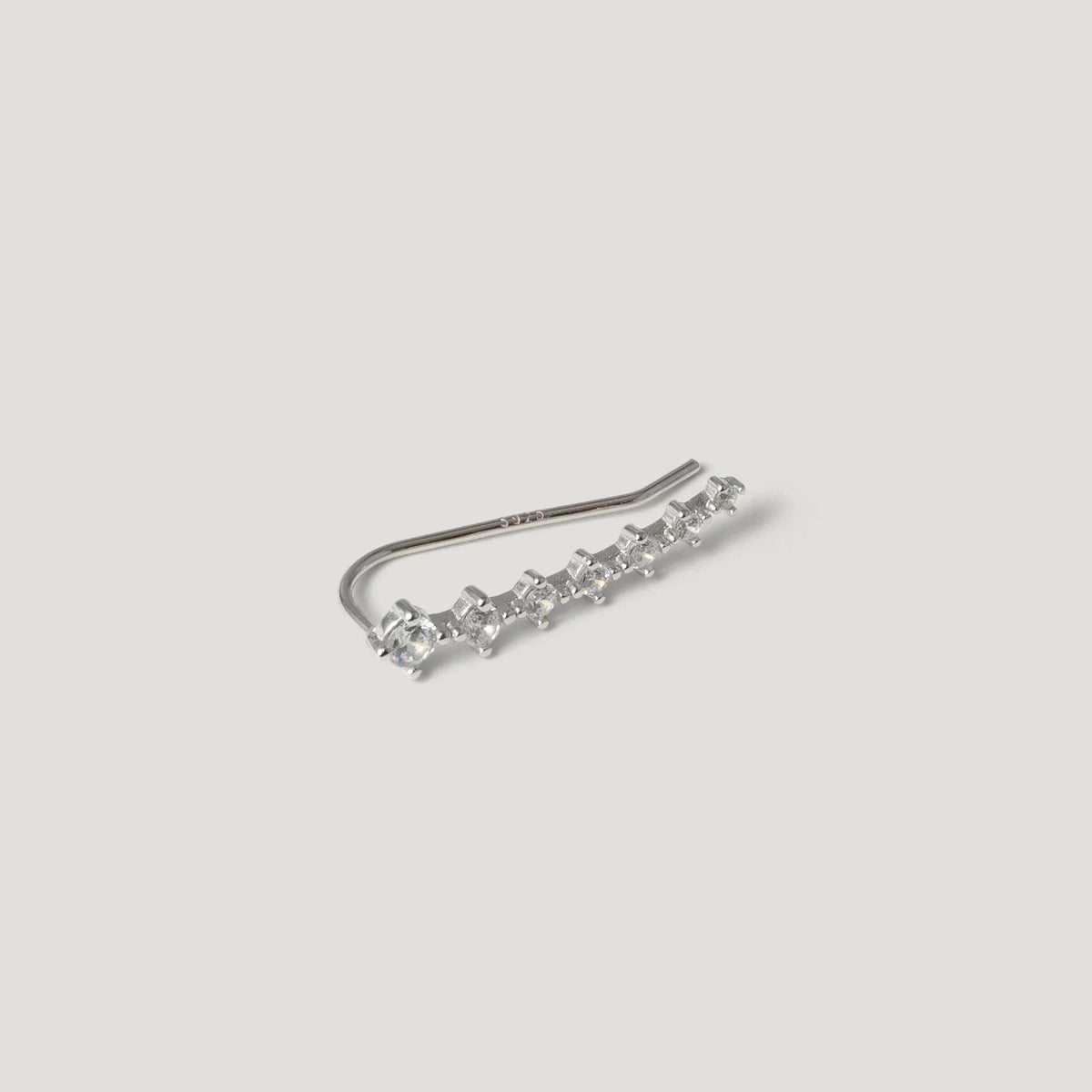 Silver ear climber earring with row of small sparkling stones on white background