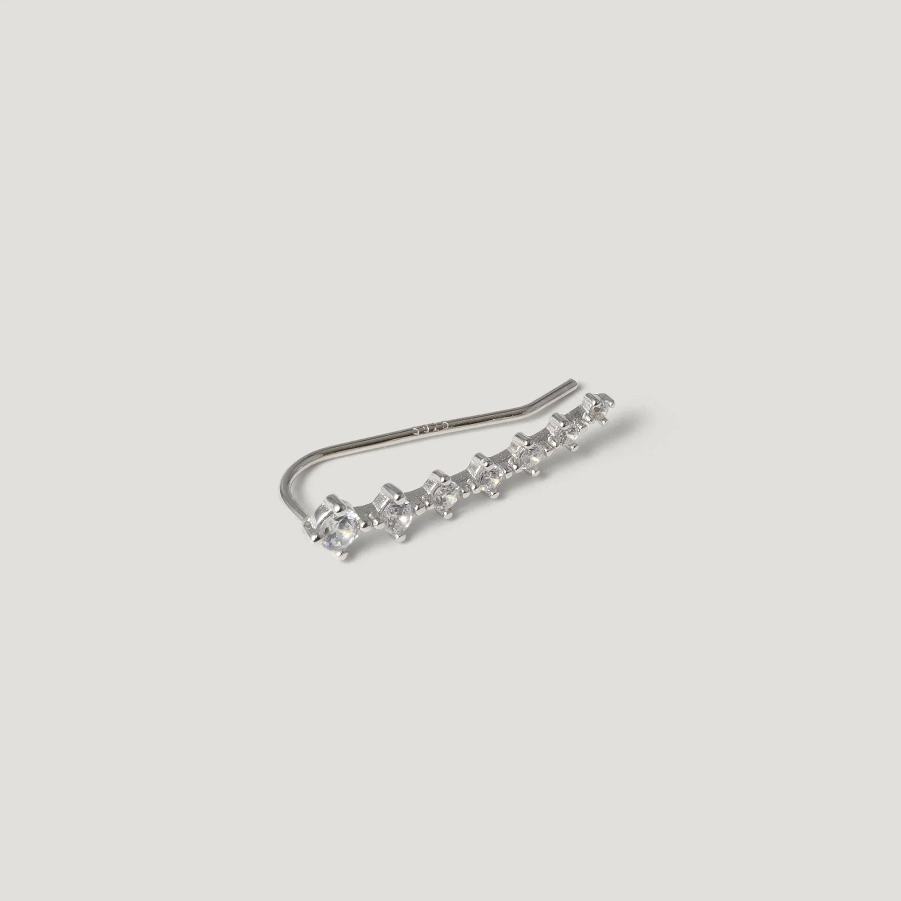 Silver ear climber earring with row of small sparkling stones on white background