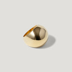 Polished gold statement ring with a bold, modern, dome-shaped design on a neutral background