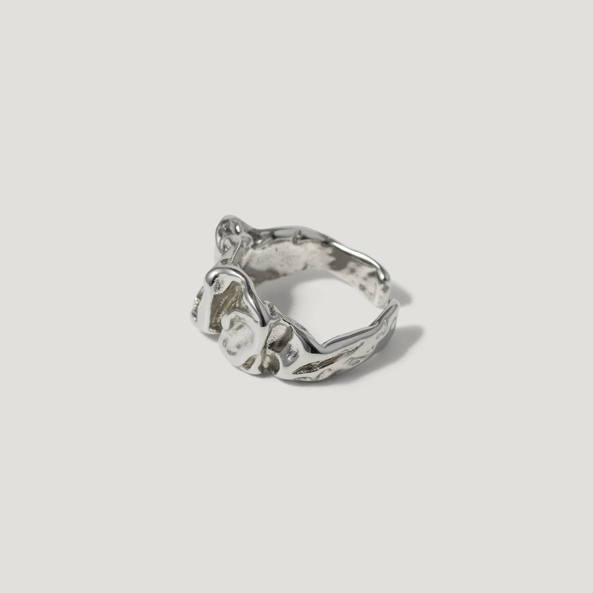 Textured silver ring with organic, sculptural design on white background