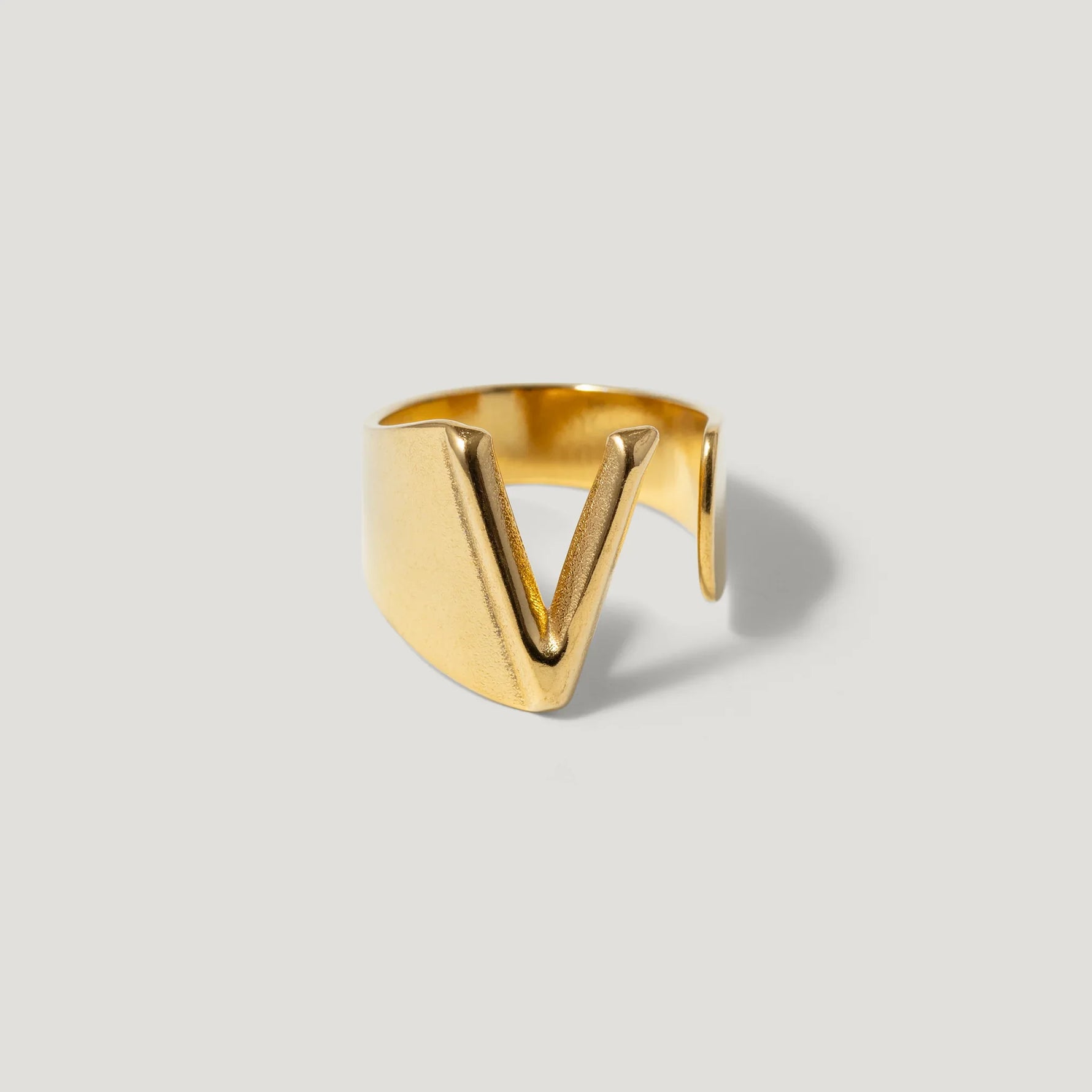 Gold open band ring with bold V-shaped design on light background
